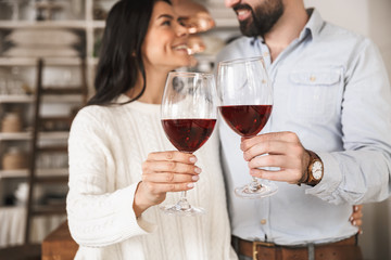 Portrait of happy european couple drinking wine from glasses while having romantic dinner at home