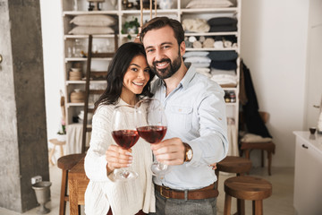 Portrait of attractive european couple drinking wine from glasses while having romantic dinner at home