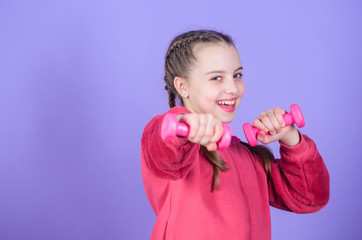 Beginner dumbbell exercises. Child hold little dumbbell violet background. Sport for teens. Easy exercises with dumbbell. Toward healthier body. Rehabilitation concept. Girl exercising with dumbbell