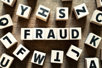 Letter block in word fraud with another block on wood background