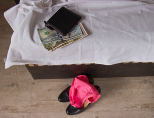 Naklejka premium Love for money is prostitution. Crumpled bed, underwear and money as payment for sex. Panties are on women's shoes.