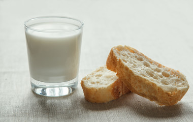 Glass of milk with fresh bread on a tablecloth. 