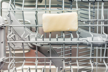 Yellow laundry soap lies in the middle compartment of the dishwasher