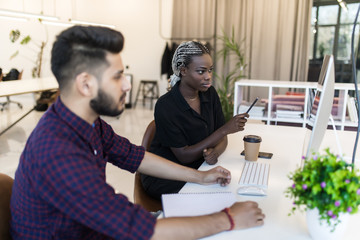 Indian Businessman and african businesswoman working with pc at modern office