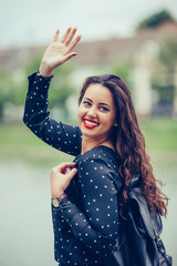 Portrait of a beautiful young woman walking outdoors, waving her hand