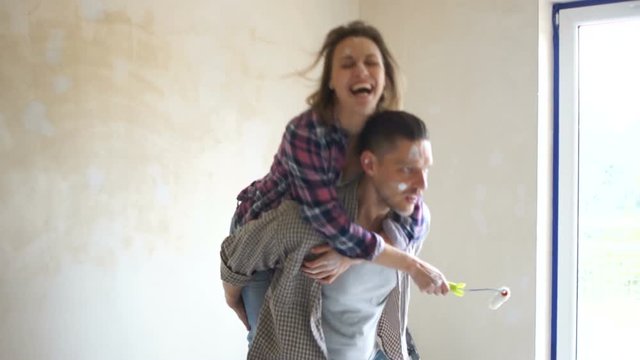 Funny video, the couple is fooling around in a new house against the background of the window. Happy couple husband and wife making repairs to their home