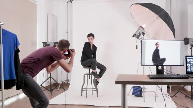 Model posing in fashion style to a professional photographer in a well lit photo studio
