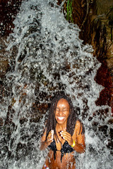 Fototapeta na wymiar Black Woman Taking Bath From Waterfall