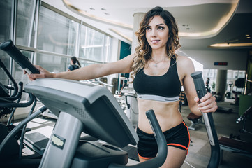 Attractive muscular fitness woman running on nordic ski in gym