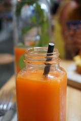 carrot and orange juice in a glass on the wooden table