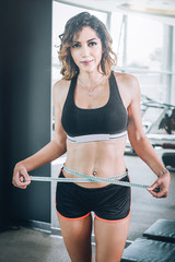 Fit fitness woman measuring her waistline with measure tape