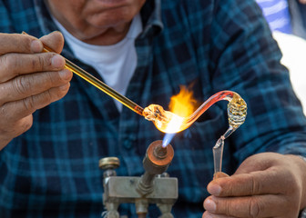 Men glassblower make handmade products  under gas burner.
