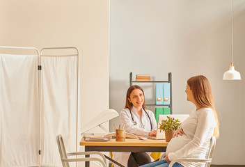 Pregnant woman is in the controlling clinic interior, woman doctor private room.