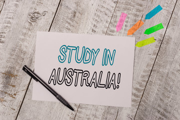 Handwriting text Study In Australia. Conceptual photo going into foreign country order complete your studies Plain note paper and line arrow stickers with pen above the wooden table
