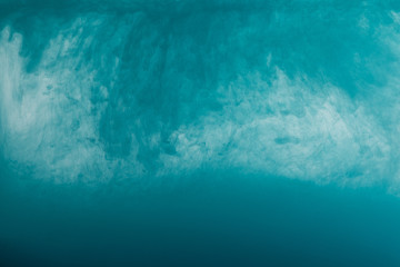 Fototapeta na wymiar Close up view of turquoise paint swirls in water