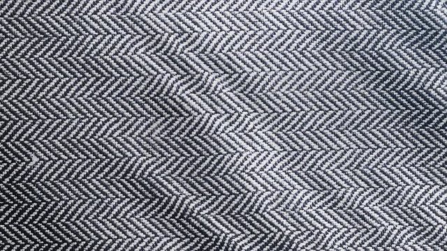 Herringbone fabric cloth background. Black and white tweed pattern, weaving, textile material is waving. 