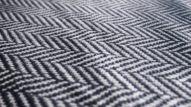Herringbone fabric cloth close up background. Macro shot of black and white tweed pattern, weaving, textile material is waving. 