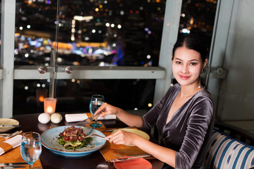 Asian Beautiful Woman have Dinner in luxury roof top restaurant with secret recipe Menu on plate course set of Spanish food Cuisine culinary which a bit hot and unique taste on wooden table.