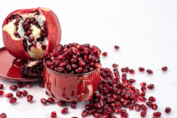 on a white background, isolated bloody red pomegranate seeds in a red cup and on a red plate