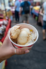 Kanom Krok, the typical thai coconut pancake in the hand of a woman on the night market in Chiang Mai, Thailand