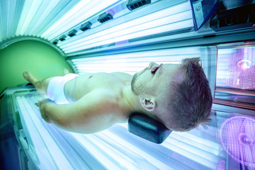 Attractive muscular man in a sunbed