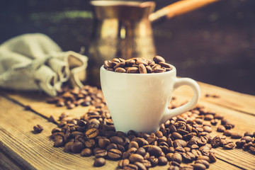 Coffee beans in white cup on the rustic wooden background. Selective focus. Shallow depth of field.