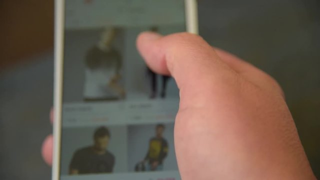 man looking and chooses clothing in smartphone