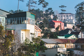 Fototapeta premium Houses on the hill cover by morning fog and sunlight in Da Lat, Vietnam
