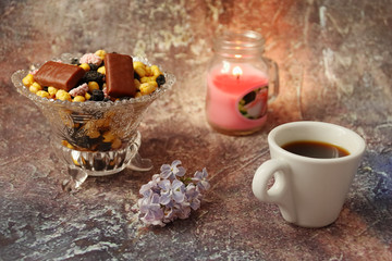 Morning coffee in a hurry: a cup of coffee, flowers in a vase, dried fruits and sweets in a vase, a burning candle.