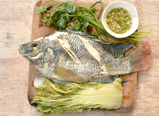 steamed mango fish with vegetable dipping spicy sauce on wooden chop block