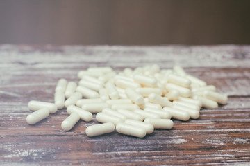 Fototapeta na wymiar White capsules pills on old wooden table background. Medical concept.