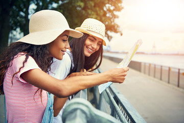 Smiling diverse female friends look at a map