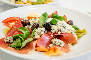 Delicious Italian pasta in a plate on a white table in a restaurant. Close-up.