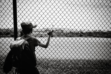 Kind schaut durch Zaun