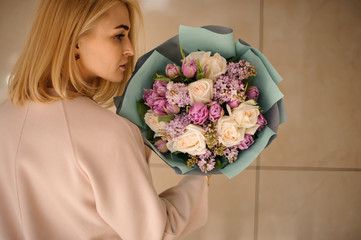 Blond girl stands with bouquet with purple flowers