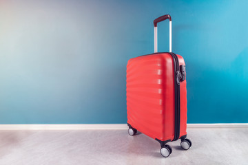 Bright and stylish cabin size suitcase as holiday concept against dark blue background, copy space. Easy travel with little baggage