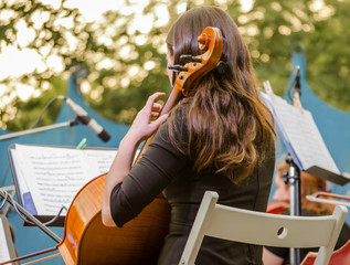 young brunette girl playing the cello on the street