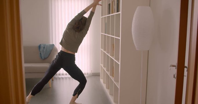 Rear portrait of tender caucasian prima ballerina dances charmingly being concentrated.
