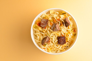 Paper cup with instant ramen noodles with beef and vegetables.