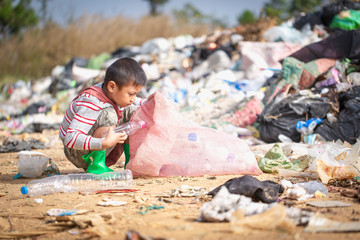 environment Earth Day, Child sitting to separate garbage to be recycled. The concept helps reduce...
