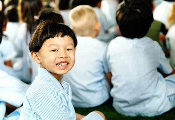 Boy student sits on row on pupils background in back to school concept
