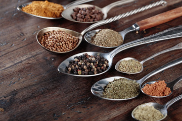 Different spices in  spoons on a wooden background.