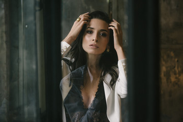Young brunette woman posing in a suit by the window