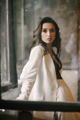 Fototapeta premium Young brunette woman posing in a suit by the window