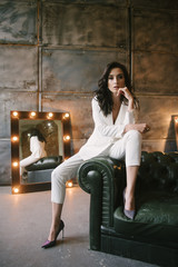 Young brunette woman posing in a suit sitting on a sofa