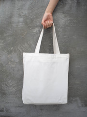 Blank white tote bag canvas fabric with handle mock up design. Close up of woman hand holding eco...
