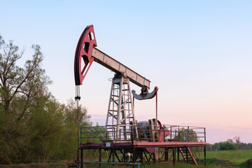 Oil and gas production equipment running at sunset