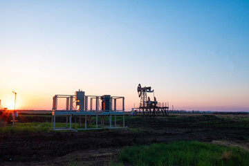 Oil and gas production equipment running at sunset