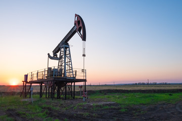 Oil and gas production equipment running at sunset