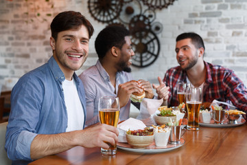Diverse Friends Eating Burgers And Drinking Beer In Pub